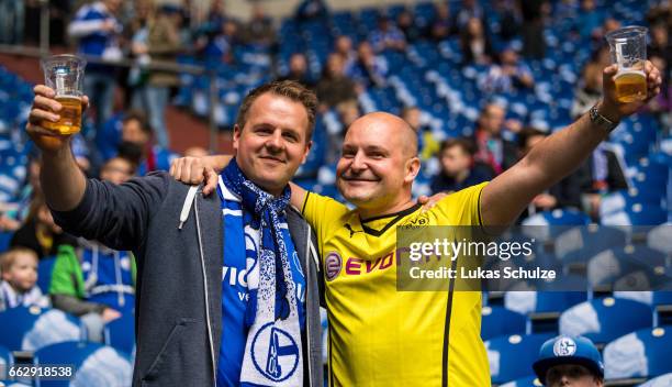 Fan of Dortmund and a fan of Schalke sit together on the tribune prior to the Bundesliga match between FC Schalke 04 and Borussia Dortmund at...