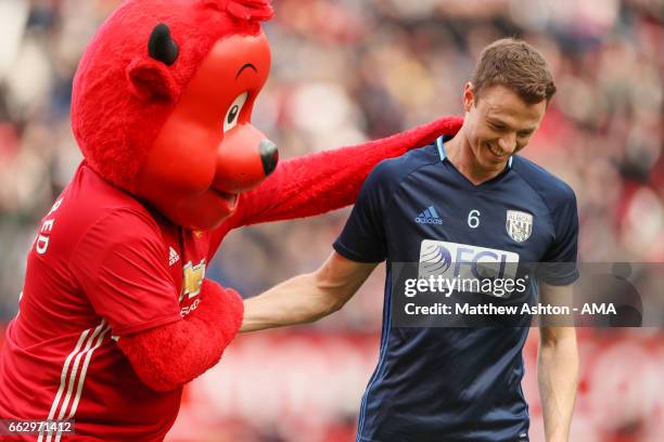 Manchester United mascot Fred The Red greets Jonny Evans of West Bromwich Albion prior to the Premier League match between Manchester United and West...