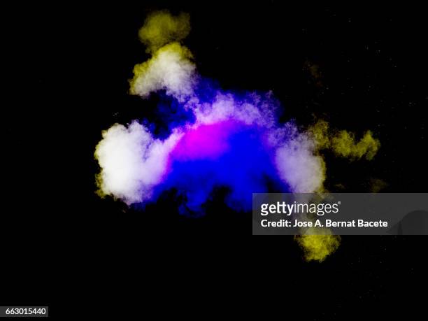 explosion of a cloud of powder of particles of  colors yellow and blue on a black background - partícula stock-fotos und bilder