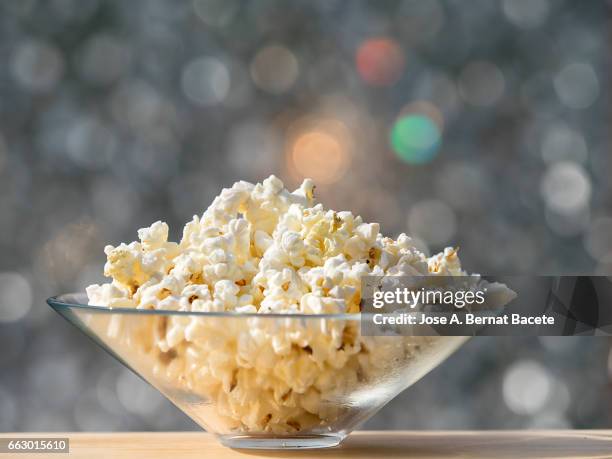 bowl of popcorn, on a wooden table lit by sunlight - rayado stock pictures, royalty-free photos & images