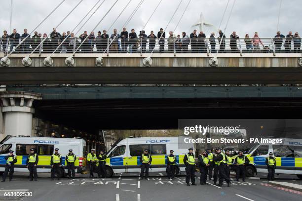 Members of the public are held on a bridge while Police block a road during a demonstration by Britain First and English Defence League in London.