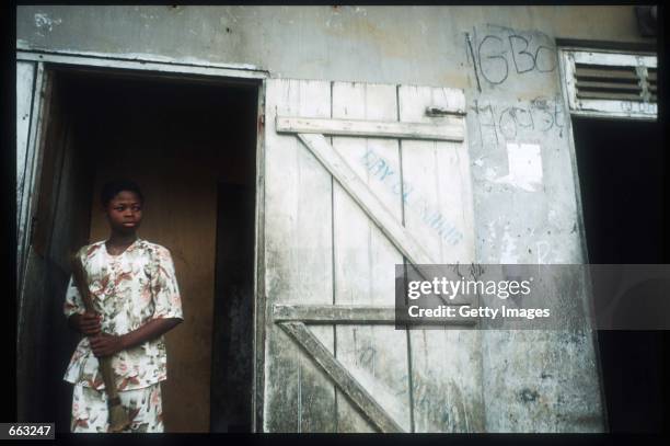 Woman stands in a doorway December 15, 1999 in the Ajegunle area of Lagos, Nigeria. Signs painted on the fronts of the houses indicate that the...