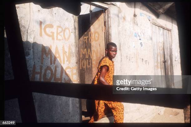 Man leaves a house December 15, 1999 in the Ajegunle area of Lagos, Nigeria. Signs painted on the fronts of the houses indicate that the residents...