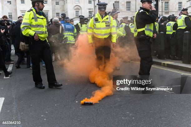 Police officer kicks away a flare during clashes with members of anti-fascist groups, Unite Against Fascism and Antifaschistische Aktion during a...
