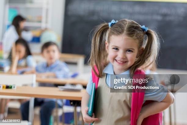 confident preschooler in her classroom - child rucksack stock pictures, royalty-free photos & images