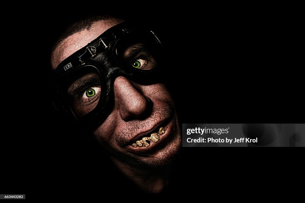 Man with motorcycle goggles or glasses, with funny fake teeth, smiling