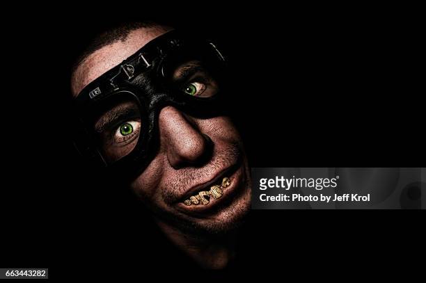 man with motorcycle goggles or glasses, with funny fake teeth, smiling - portretfoto fotografías e imágenes de stock