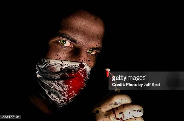 dentist looking man, wearing bloody dust mask, holding a tooth in his hand with - van de zijkant 個照片及圖片檔