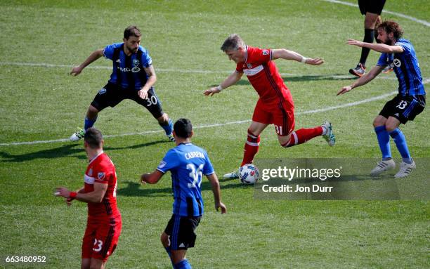 Bastian Schweinsteiger of Chicago Fire dribbles around Hernan Bernardello of Montreal Impact and Marco Donadel during the second half at Toyota Park...