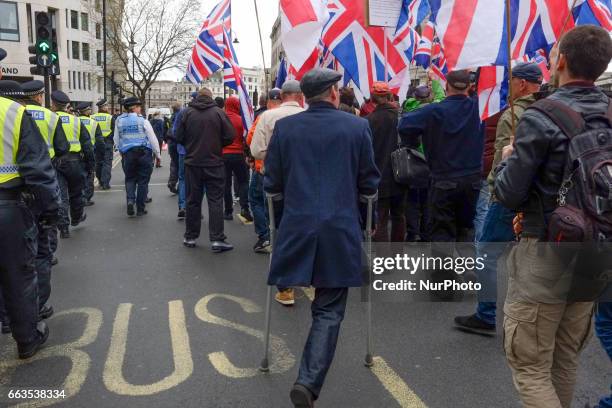 Protesters hold placards and British Union Jack flags during a protest titled 'London march against terrorism' in response to the March 22...