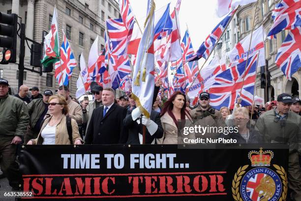 Protesters hold placards and British Union Jack flags during a protest titled 'London march against terrorism' in response to the March 22...