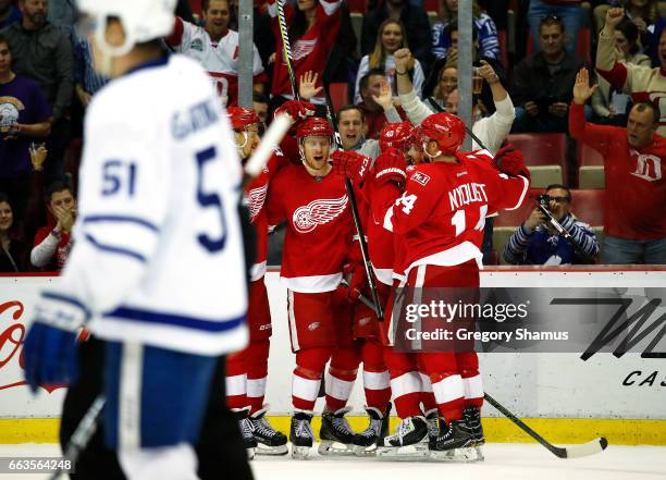 Nick Jensen of the Detroit Red Wings celebrates his second period goal with teammates behind Jake Gardiner of the Toronto Maple Leafs at Joe Louis...