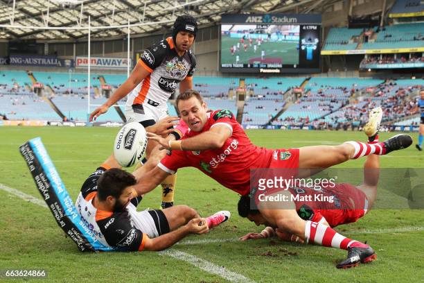 James Tedesco of the Tigers drops the ball over the line as Jason Nightingale of the Dragons defends during the round five NRL match between the...
