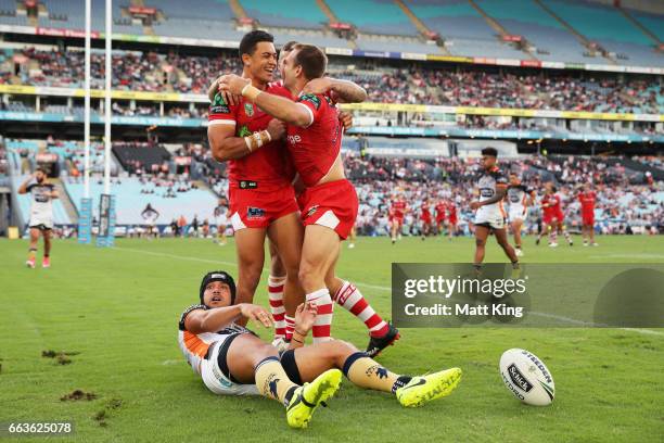 Jason Nightingale of the Dragons celebrates with team mates after scoring a try as David Nofoaluma of the Tigers looks on during the round five NRL...