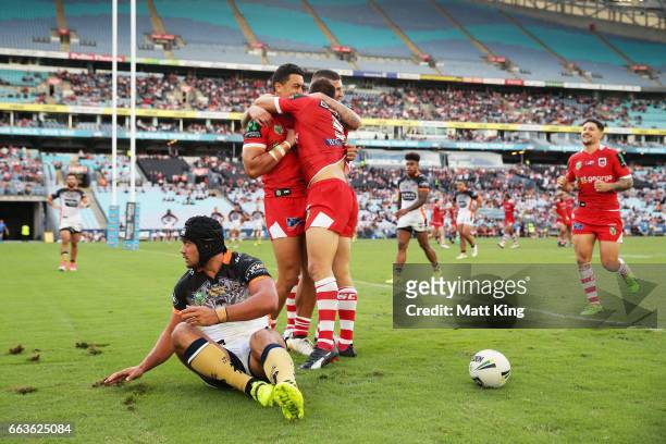 Jason Nightingale of the Dragons celebrates with team mates after scoring a try as David Nofoaluma of the Tigers looks on during the round five NRL...
