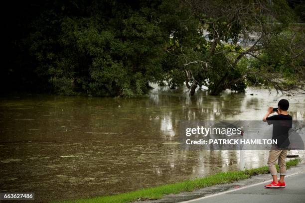 Resident takes photos as floodwaters caused by Cyclone Debbie recede in Beenleigh on April 2, 2017. Rising floods continued to plague parts of...