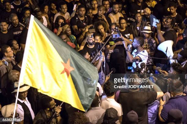 Man waves a Guyanese flag as Guiana workers union secretary general Davy Rimane adresses the protesters after negotations between Guyanese...