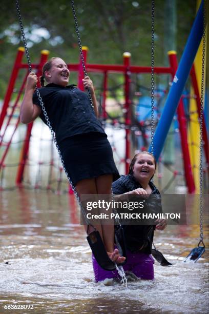 Crystal Warner and Sharnia Johns play on playground equipment as floodwaters caused by Cyclone Debbie recede in the town of Beenleigh on April 2,...