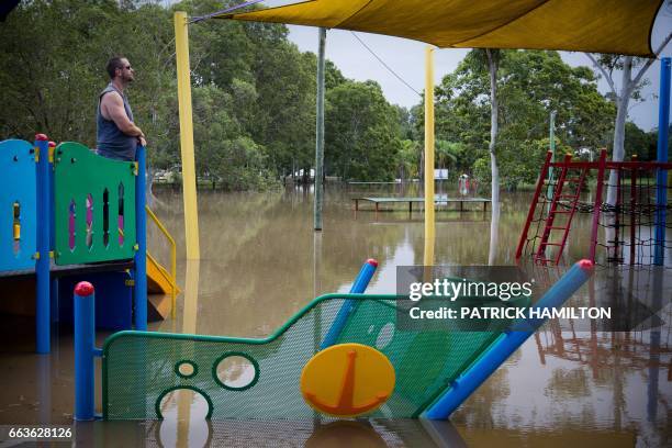 Residents watch as floodwaters caused by Cyclone Debbie recede in the town of Beenleigh on April 2, 2017. Rising floods continued to plague parts of...