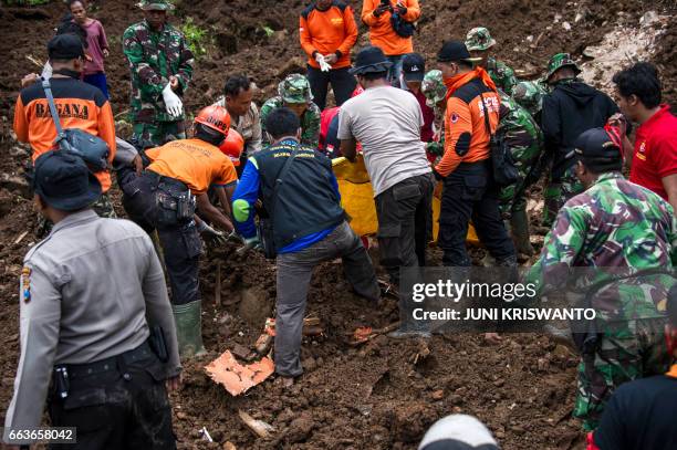Indonesian rescuers recover the body of a woman from the scene after a wall of mud slammed onto houses from a hillside following heavy rainfall in...