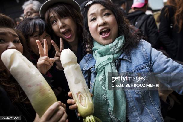 Women hold radishes carved to resemble phalluses during the annual Kanamara Festival at Kanayama Shrine in Kawasaki on April 2, 2017. Japanese...