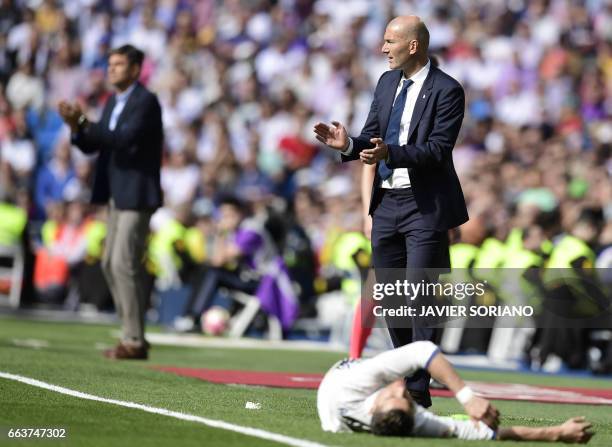 Real Madrid's French coach Zinedine Zidane applauds as Real Madrid's Portuguese forward Cristiano Ronaldo lies in front of him during the Spanish...