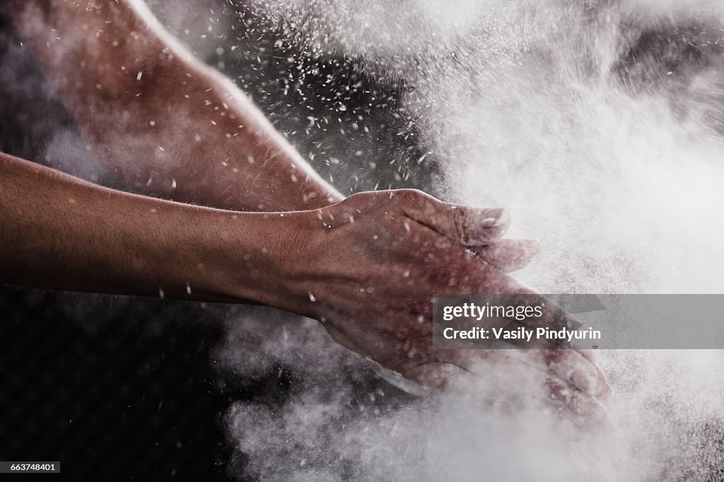 Cropped image of womans hand dusting chalk powder for exercising