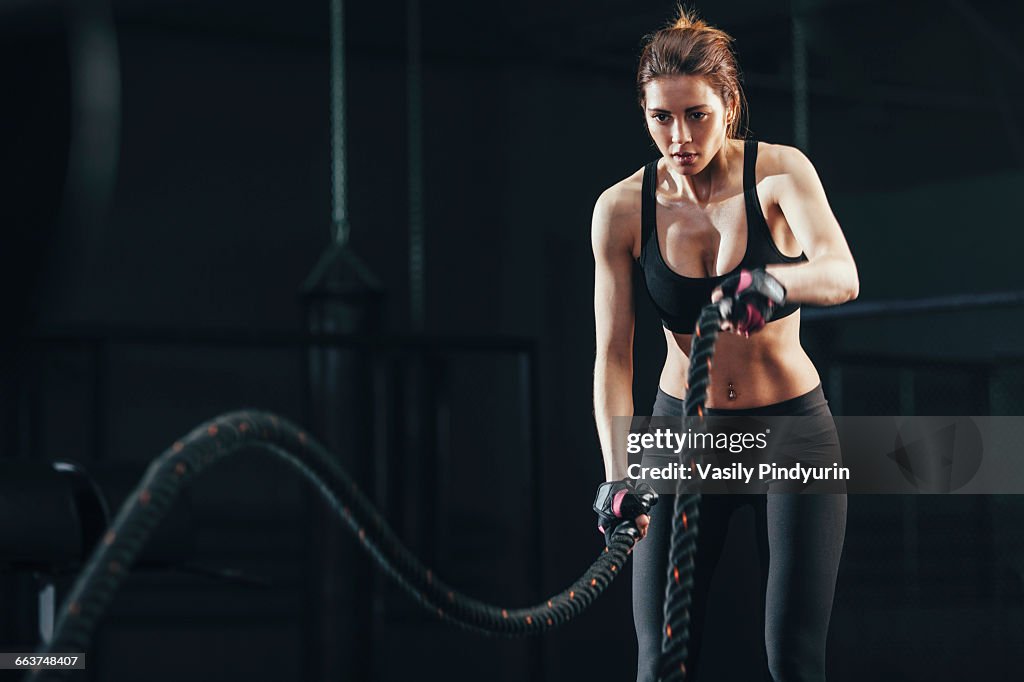 Young woman exercising with rope at gym