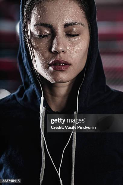 woman in hooded shirt with sweat on face at gym - schweiß stock-fotos und bilder