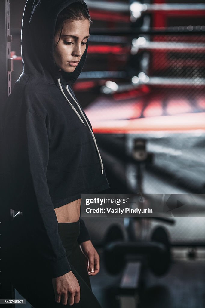 Side view of thoughtful young woman standing at gym