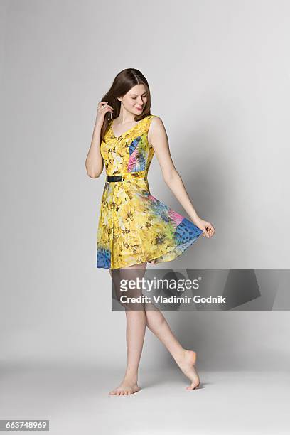 beautiful woman holding dress while standing against white background - yellow dress stock pictures, royalty-free photos & images