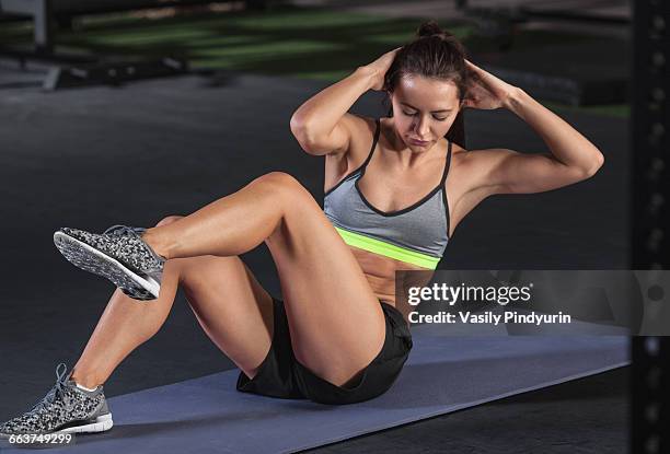 young woman doing sit-ups on exercise mat at gym - sit up foto e immagini stock