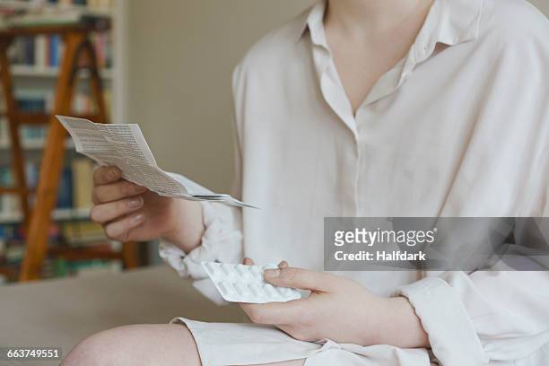 midsection of woman reading prescription of pills at home - cure berlin 2016 stock pictures, royalty-free photos & images