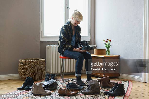 happy woman holding shoes while sitting at home - women trying on shoes 個照片及圖片檔
