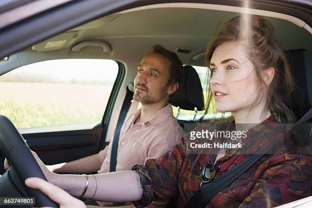 female driving while sitting besides man in car - couple car stock-fotos und bilder