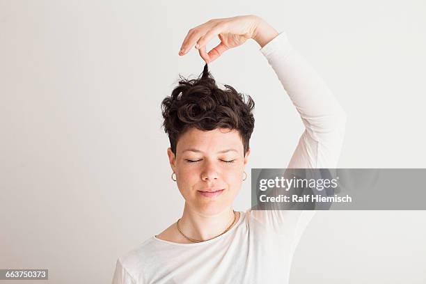close-up of happy mid adult woman holding her hair against white background - short hair women stock-fotos und bilder