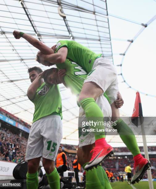 Mario Gomez of Wolfsburg celebrates scoring his third goal with Robin Knoche and Maximilian Arnold during the Bundesliga match between Bayer 04...
