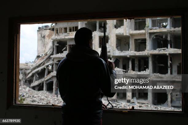 Syrian rebel fighter stands behind a window in a heavily damaged neighbourhood of Daraa, in southern Syria, on April 2, 2017.
