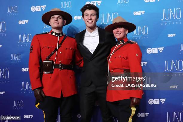 Shawn Mendes poses with RCMP officers as he arrives on the red carpet before the JUNO awards at the Canadian Tire Centre in Ottawa, Ontario, on April...