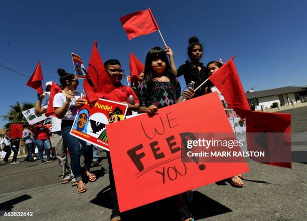 Casey Rojas carries a 'We Feed You' banner as she shows support for farm workers marching against US President Donald Trump's anti-immigrant policies...
