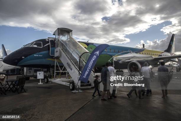 Attendees walk past an Embraer SA 195 jet turbine aircraft operated by Azul Brazilian Airlines SA during the International Brazil Air Show at Rio...