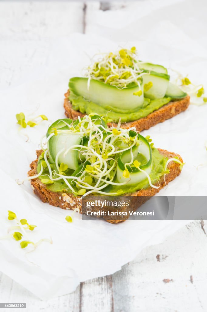 Healthy whole grain bread with avocado, cucumber and sprouts