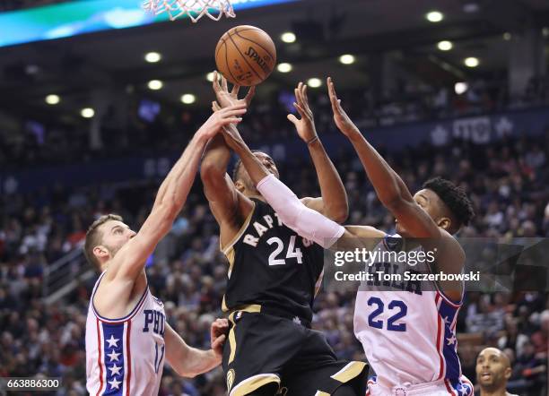 Norman Powell of the Toronto Raptors is stopped as he goes to the basket by Nik Stauskas of the Philadelphia 76ers and Richaun Holmes during NBA game...