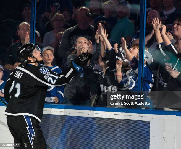 Brayden Point of the Tampa Bay Lightning celebrates the win by tossing an autographed puck to fans after the game against the Dallas Stars at Amalie...