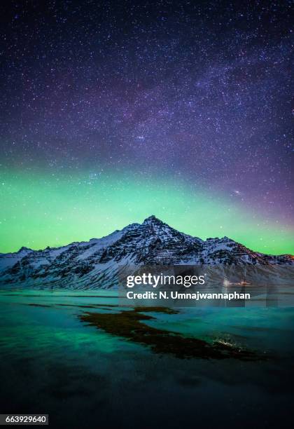 snowy mountain with the aurora and milky way in southern iceland - reykjavik foto e immagini stock