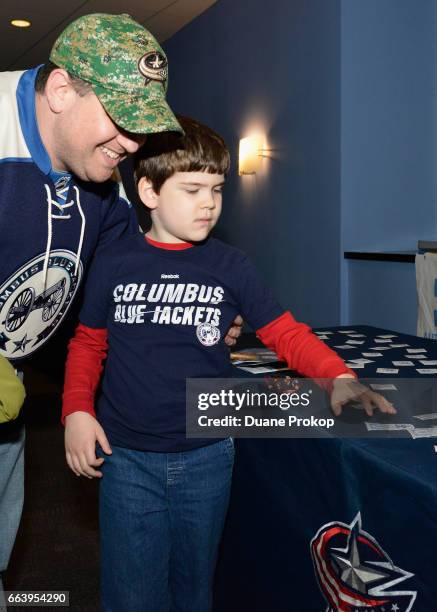 Corey Harrison picks out a temporary tattoo with his son Cole Harrison during Autism Speaks Light It Up Blue at Nationwide Arena on April 2, 2017 in...