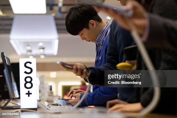 An employee, center, uses a Samsung Electronics Co. Galaxy S8 smartphone at the company's D'light flagship store in Seoul, South Korea, on Monday,...