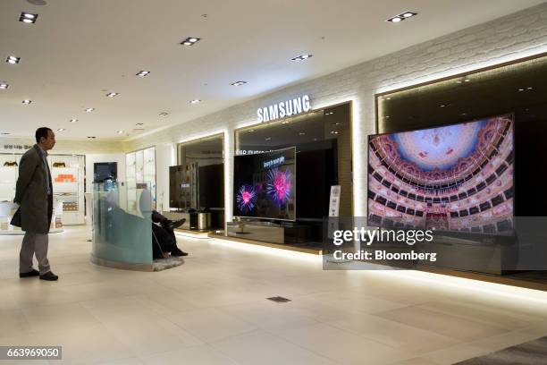 Customers look at a Samsung Electronics Co. Curved SUHD televisions at the company's D'light flagship store in Seoul, South Korea, on Monday, April...