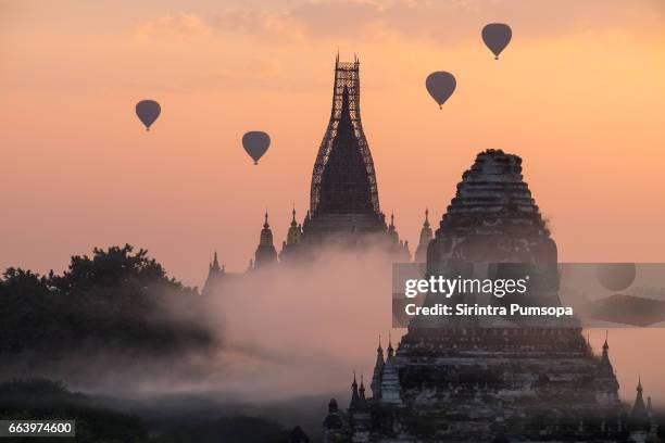 hot air balloons fly over the ananda temple in bagan plains during the morning sunrise in myanmar after big earthquake in 2016 - bagan temples damaged in myanmar earthquake stock pictures, royalty-free photos & images