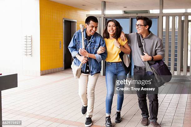 three highschool friends walking to class. - 3 teenagers stock-fotos und bilder